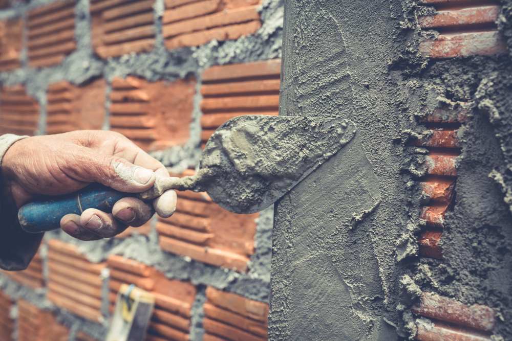 Ouvrier de construction construisant un mur en briques